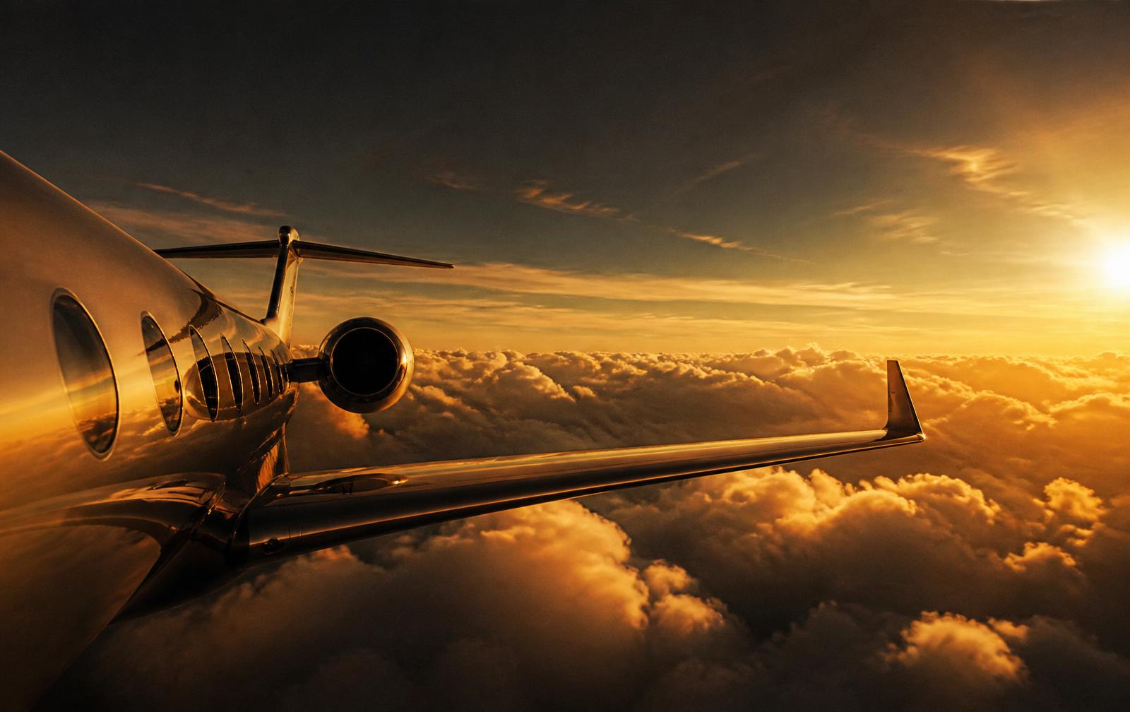 Private jet above golden clouds at sunset